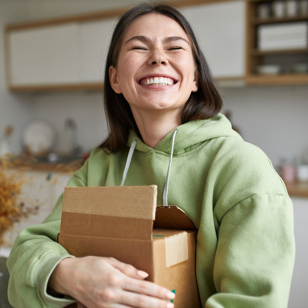 Very happy young female customer hugs shipping box from home product manufacturer