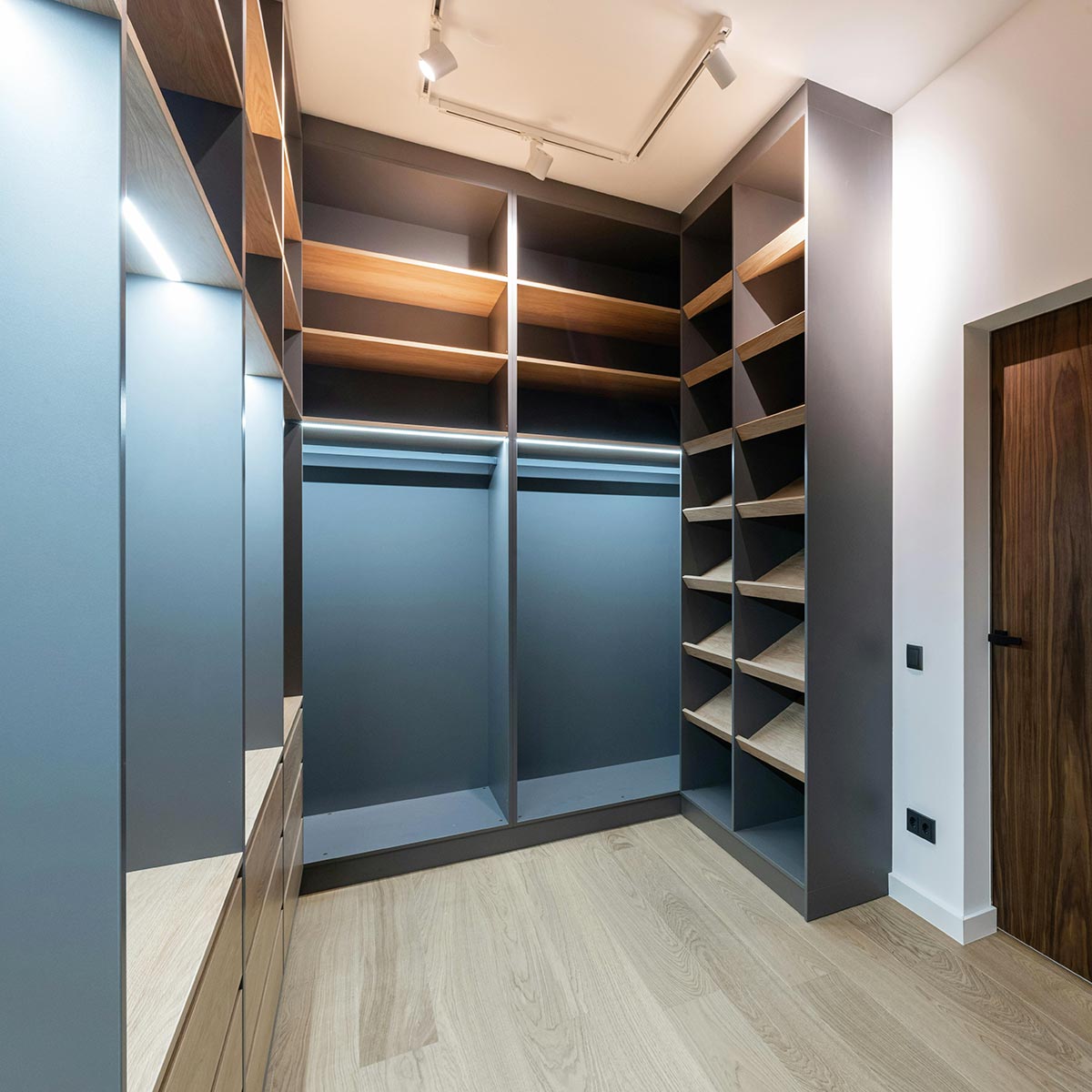 This custom closet blends color and deep rich wood tones and includes closet lighting, shelving, hanging, and shoe storage.